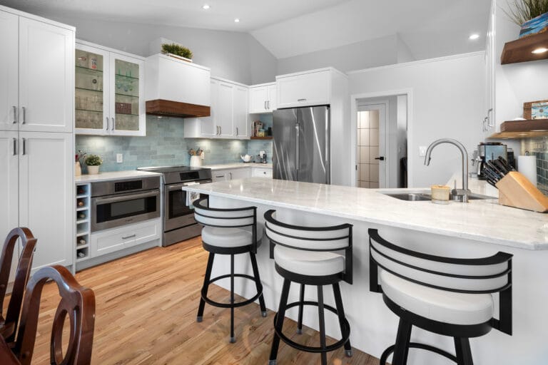 Modern kitchen design in a Custom Home featuring sleek cabinetry, stainless steel appliances, and a spacious island with bar seating, highlighted by warm wood flooring and stylish lighting.